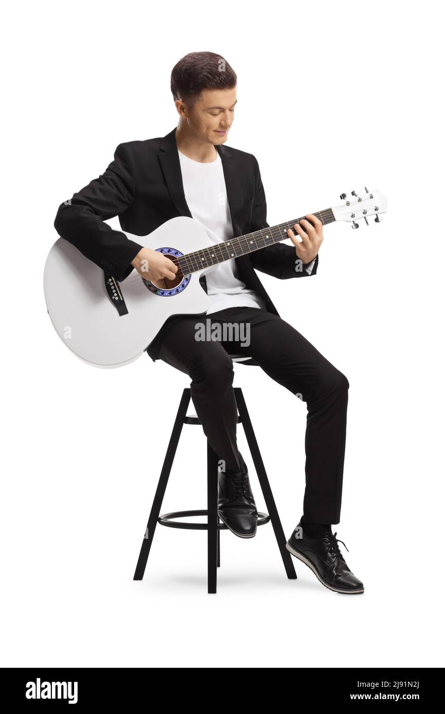 Elegant young man in a black suit sitting on a chair and playing a ...
