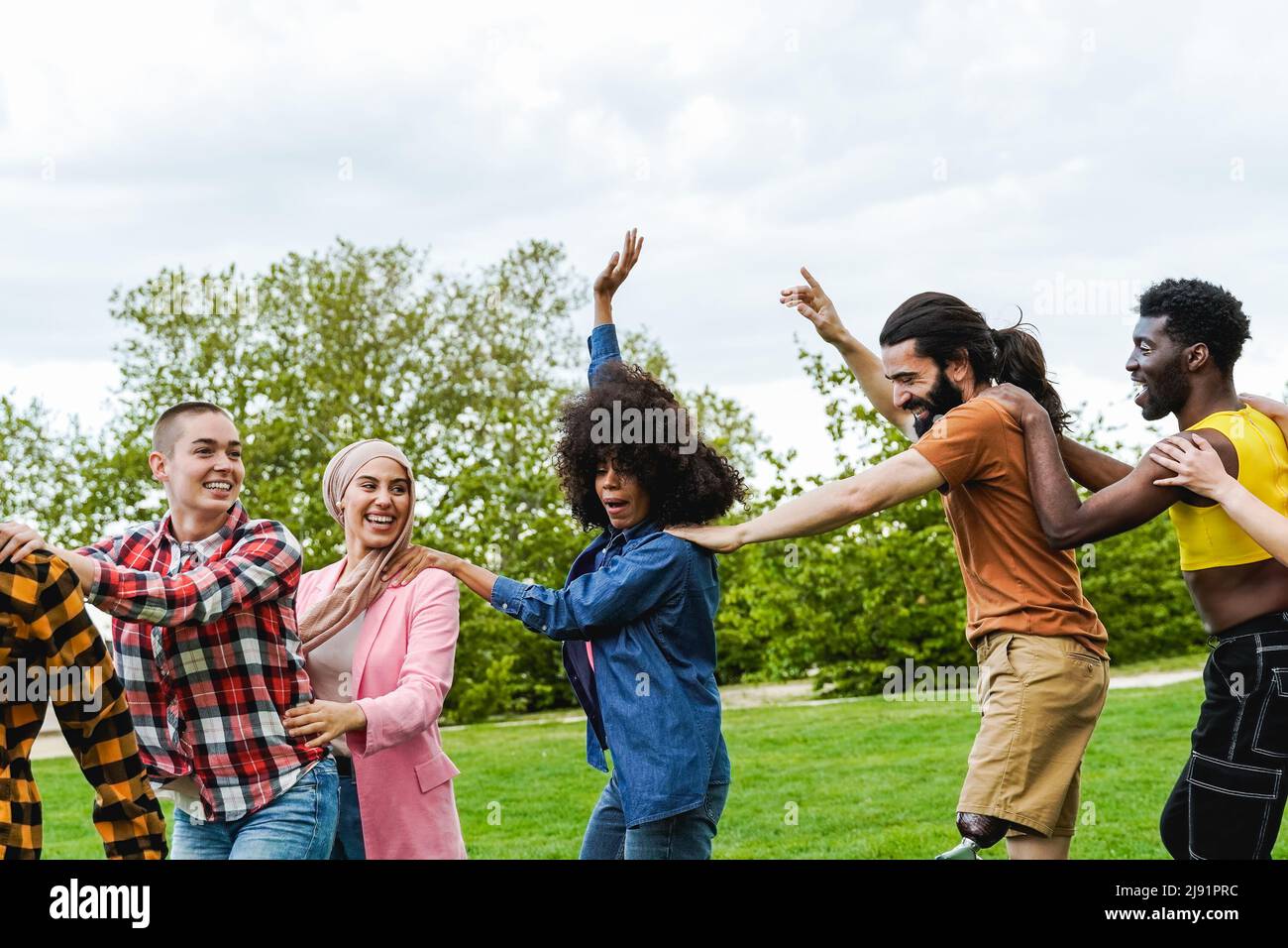 Multiethnic group of diverse friends having fun dancing together outdoor during summer vacations - Focus on man with leg prosthesis Stock Photo