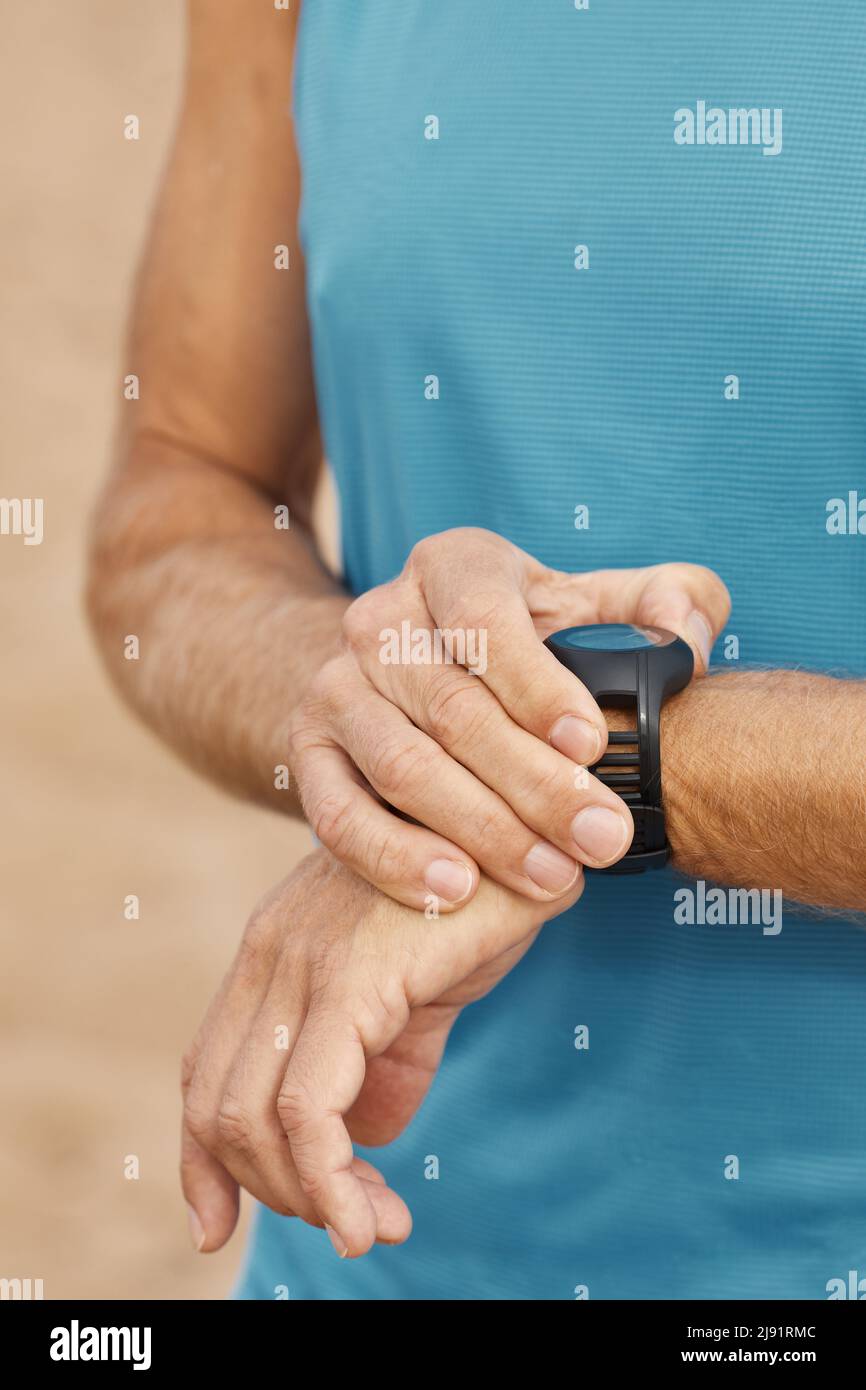 Vertical close up shot of unrecognizable aged man using his fitness bracelet Stock Photo