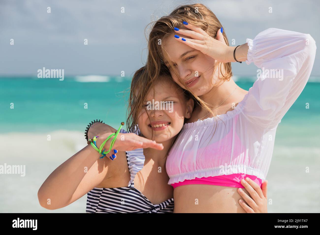 Real sisters are on the vacation, outdoor portrait of two beautiful European girls taken at the ocean coast on a sunny day Stock Photo