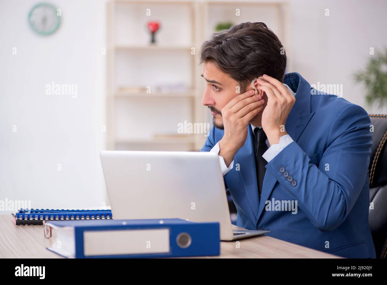 Deaf businessman employee using hearing aid in the office Stock Photo