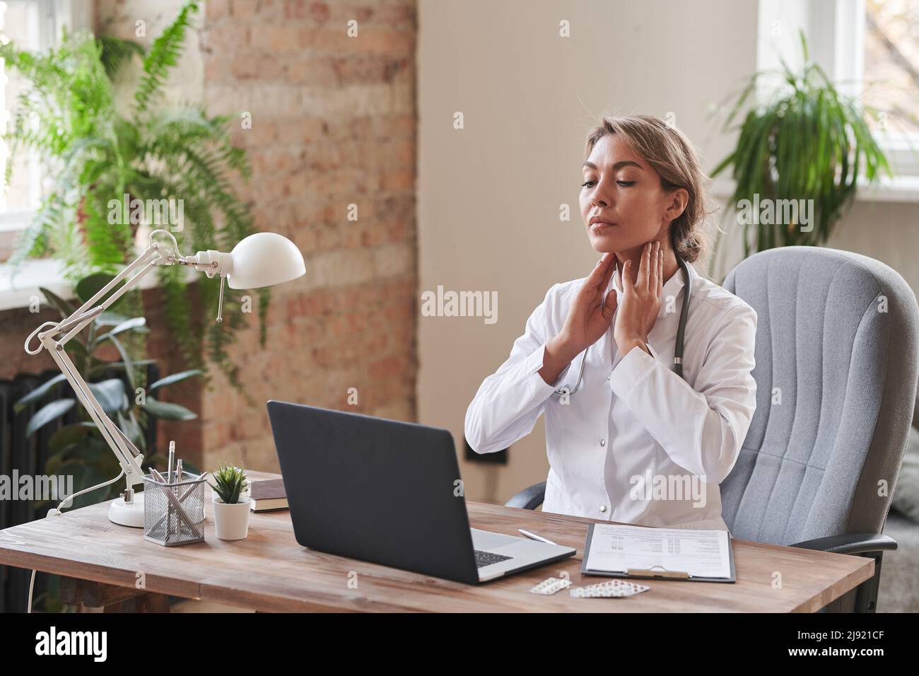 Modern female doctor sitting at desk in office demonstrating how to ...