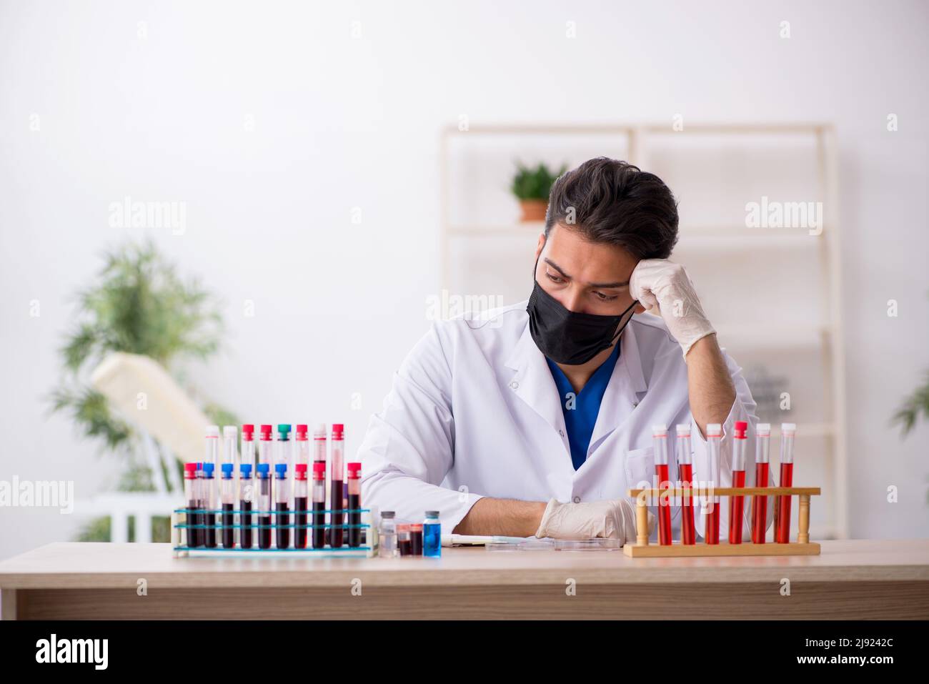 Young biochemist testing blood samples in pandemic concept Stock Photo