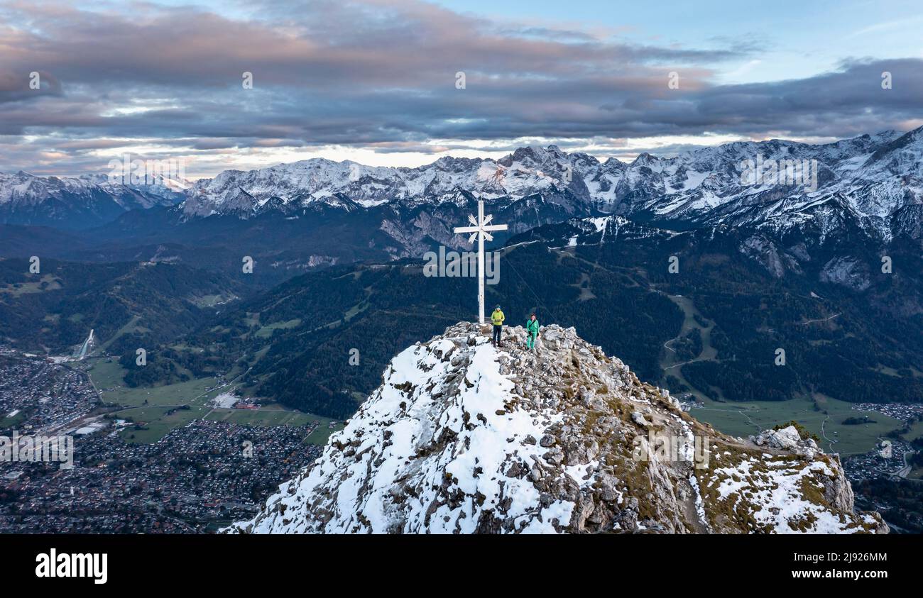 Alpine panorama with Zugspitze and summit cross of the Kramer, aerial view, mountains with snow in the evening, summit of the Kramer, Garmisch Stock Photo