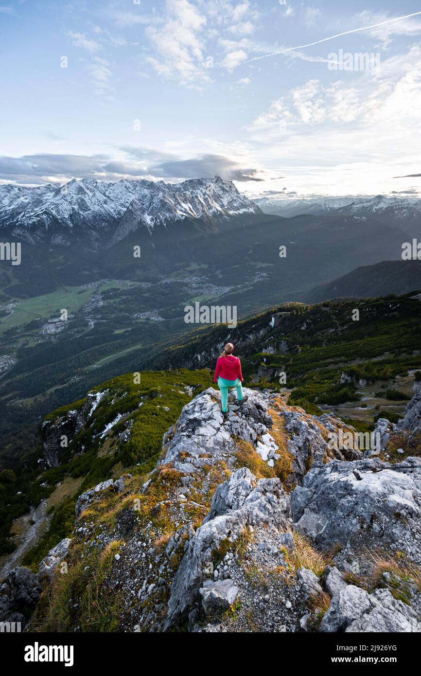 Young hiker at the Kramerspitz, Wetterstein Mountains and Zugspitze in the background, Bavaria, Germany Stock Photo