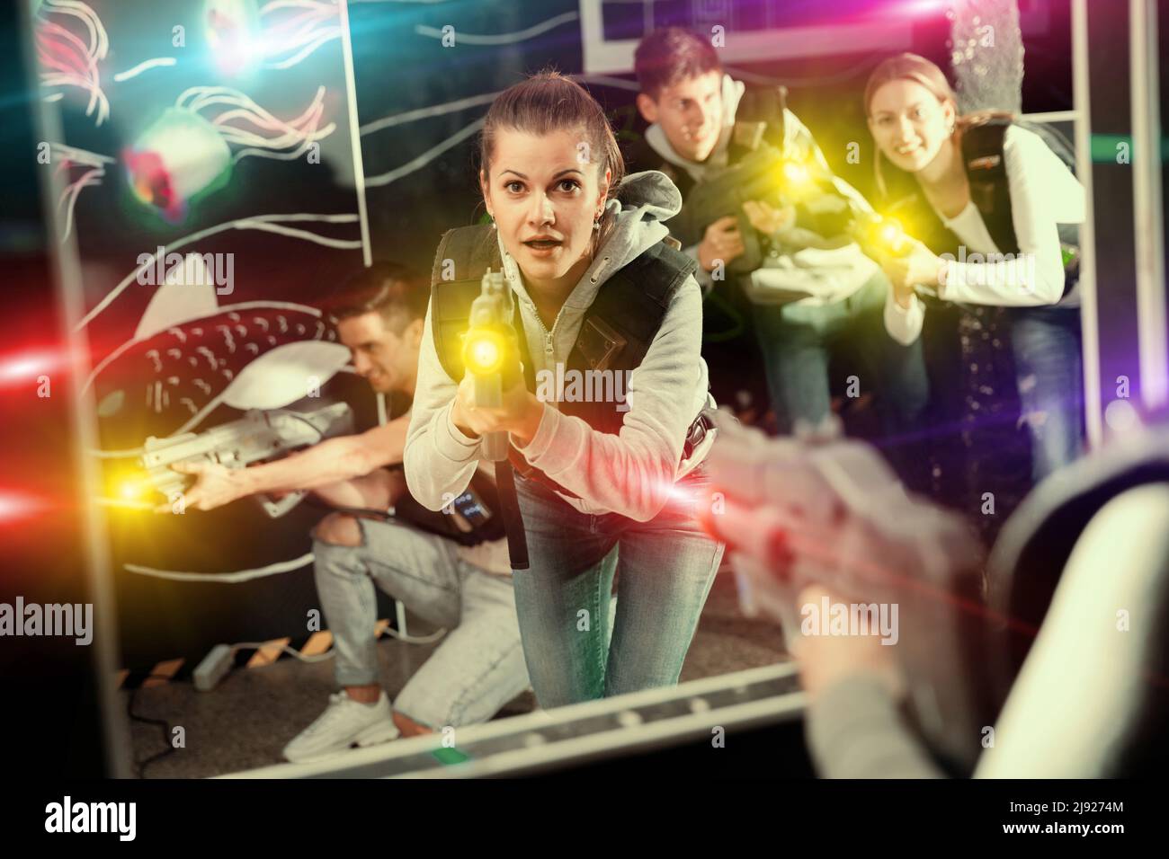Portrait of excited woman holding laser gun in arena, playing laser tag