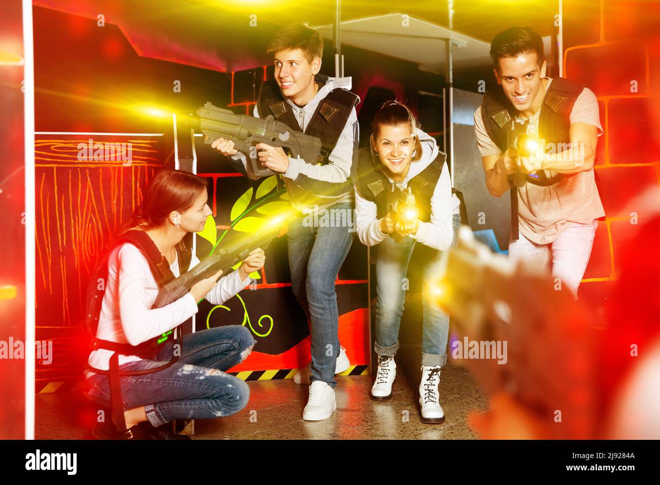 Group of young people playing laser tag game with laser guns Stock