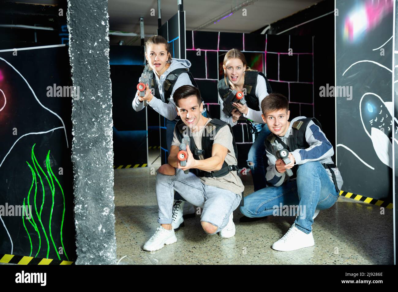 Group of adult people with laser guns having fun on dark lasertag arena