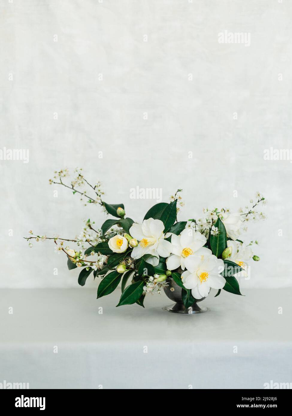 Wedding flower arrangement on a grey tablecloth against a white wall Stock Photo