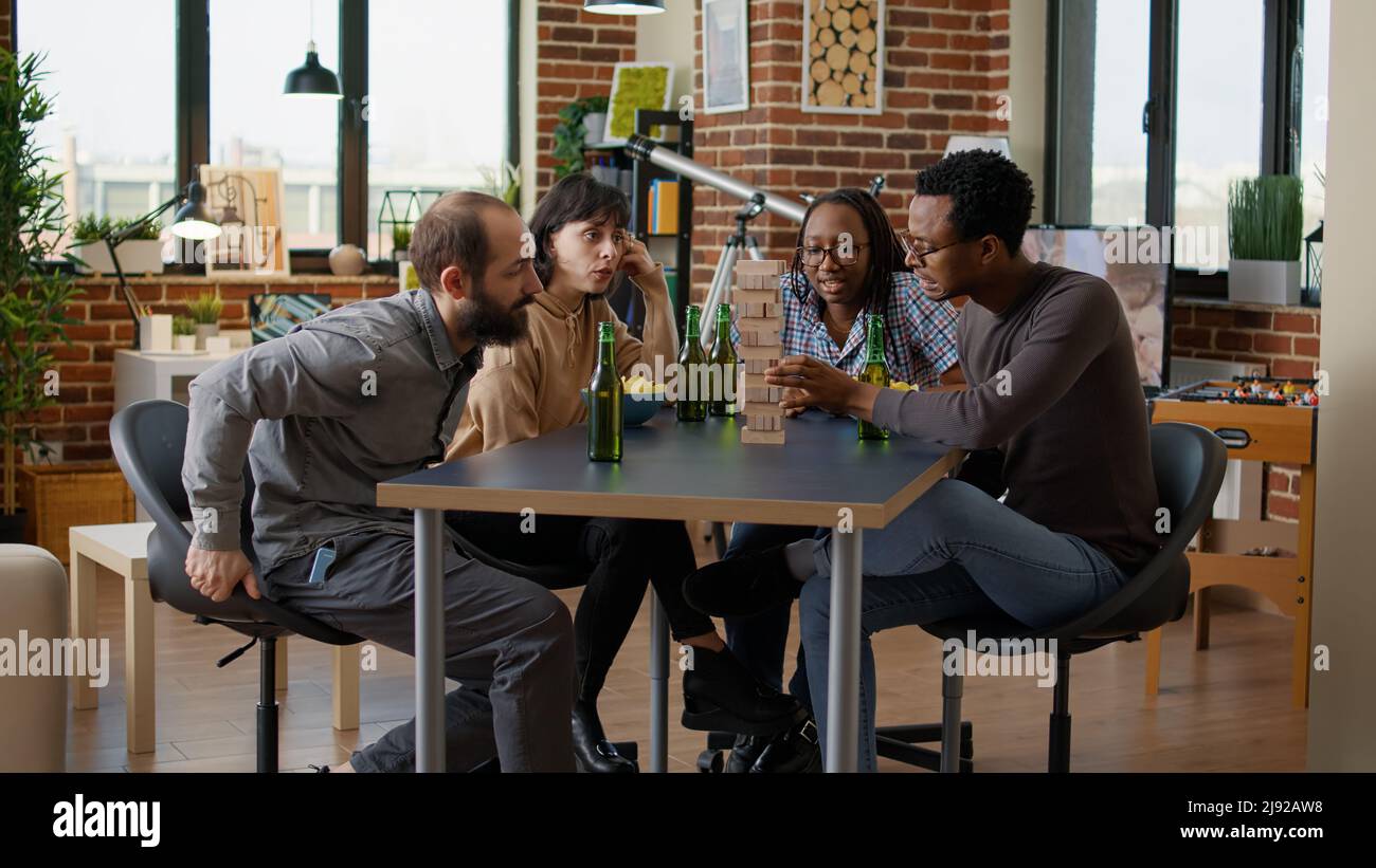 Multiethnic group of people having fun with tower pieces, playing board ...