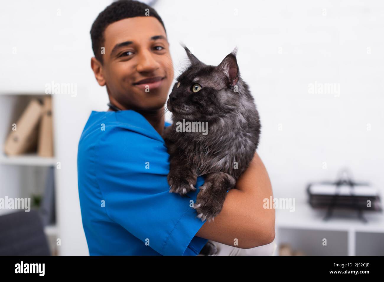 Blurred and smiling african american veterinarian in uniform holding