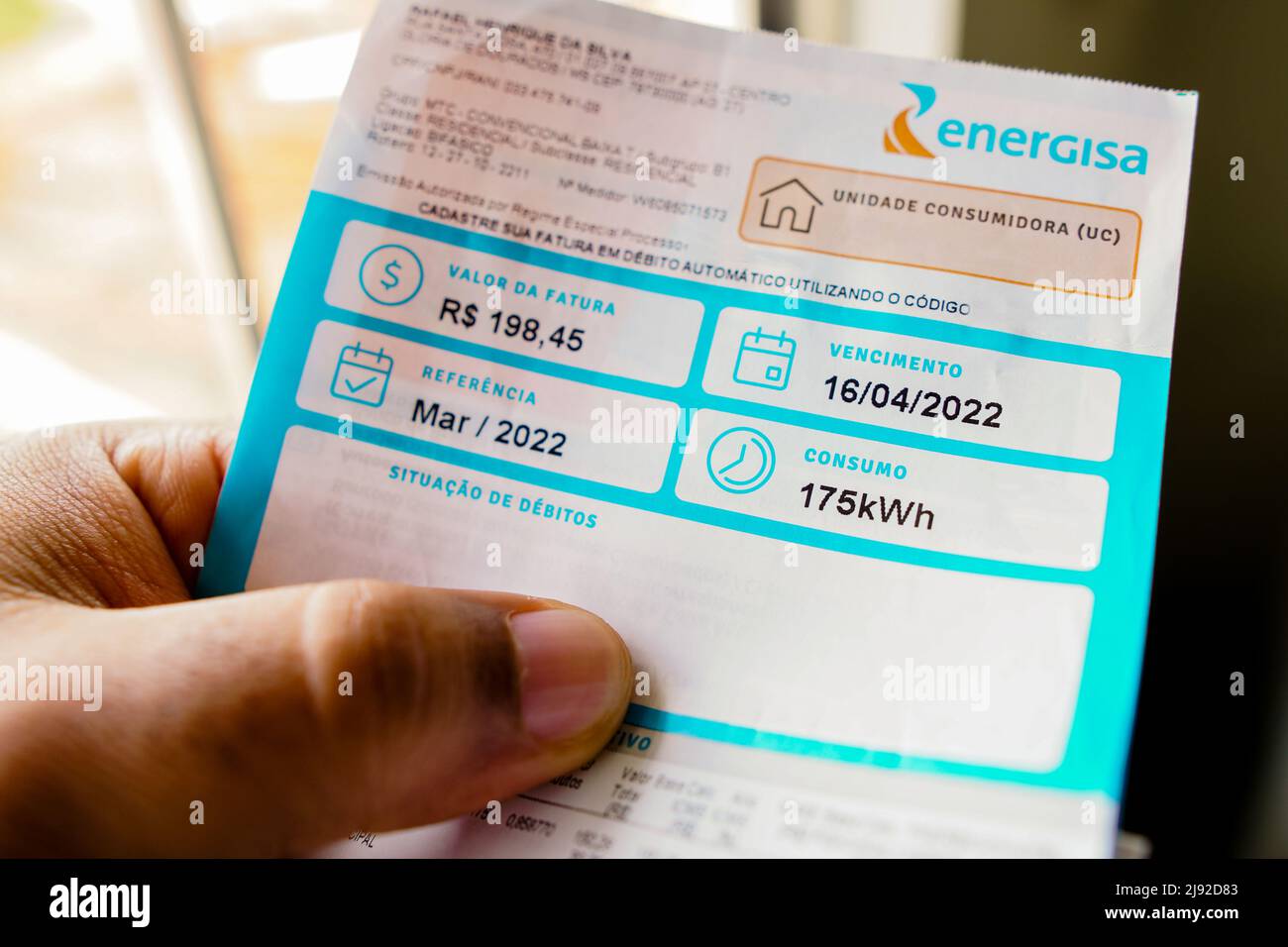 In this photo illustration, a consumer holds an electricity bill indicating monthly consumption of 175 kilowatts (kWh). Stock Photo