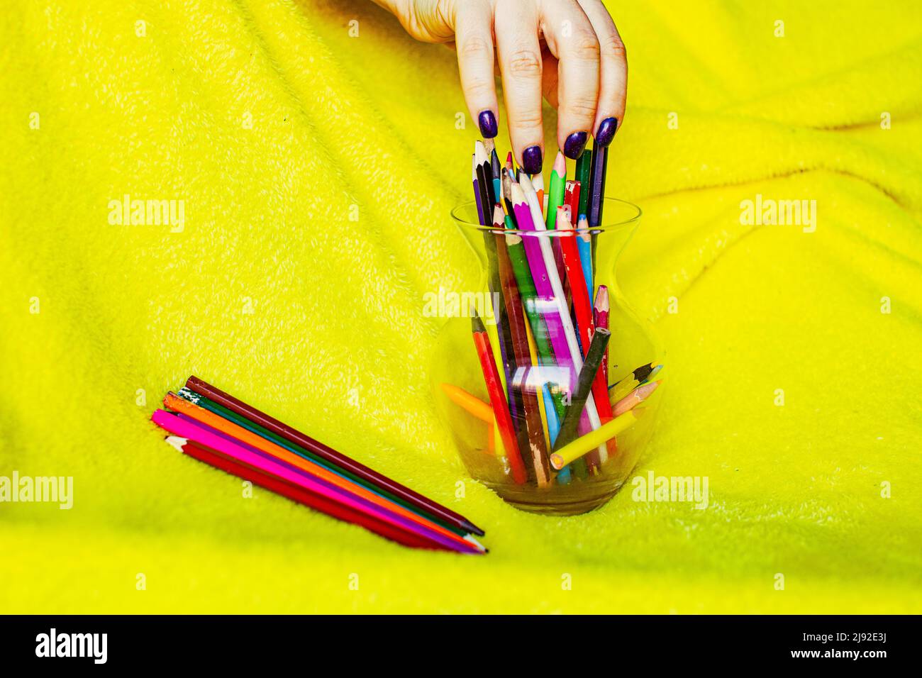 Colored pencils on the yellow background. Top view. Stock Photo
