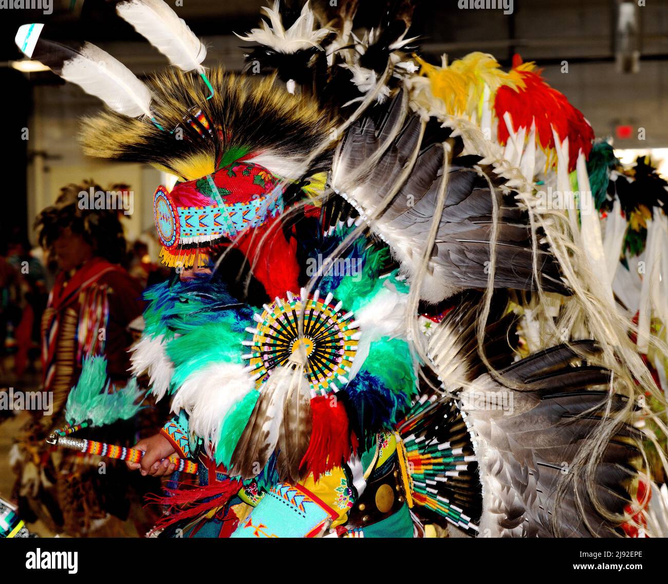 Powwow dancer in ornate feather and bustle regalia that obscures the person's features as he moves with the singing and drumming Stock Photo