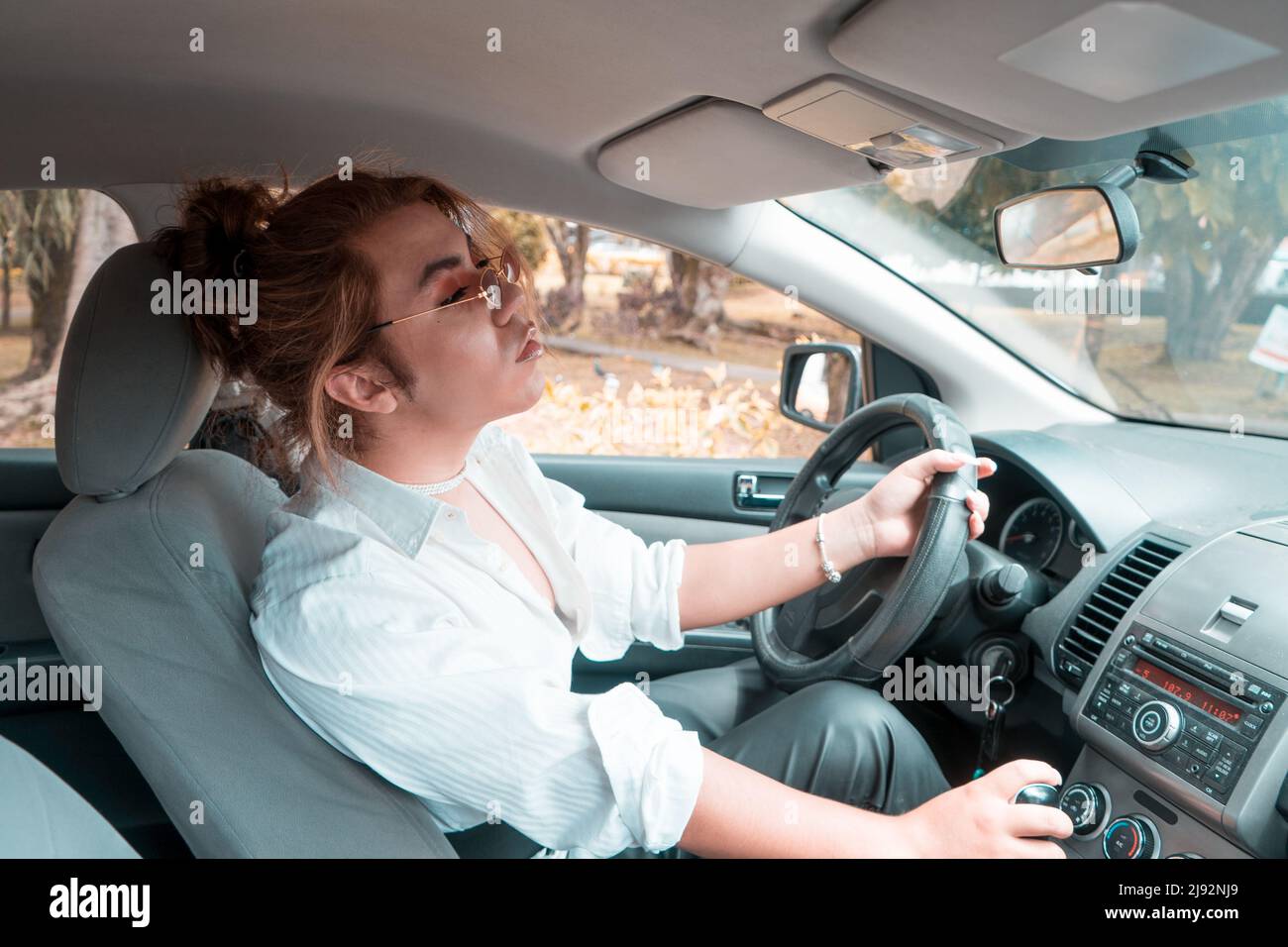 non binary young driving a car with hand on the lever looking in the