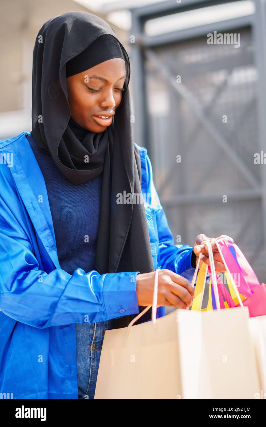 Muslim shopaholic checking purchases in paper bags Stock Photo