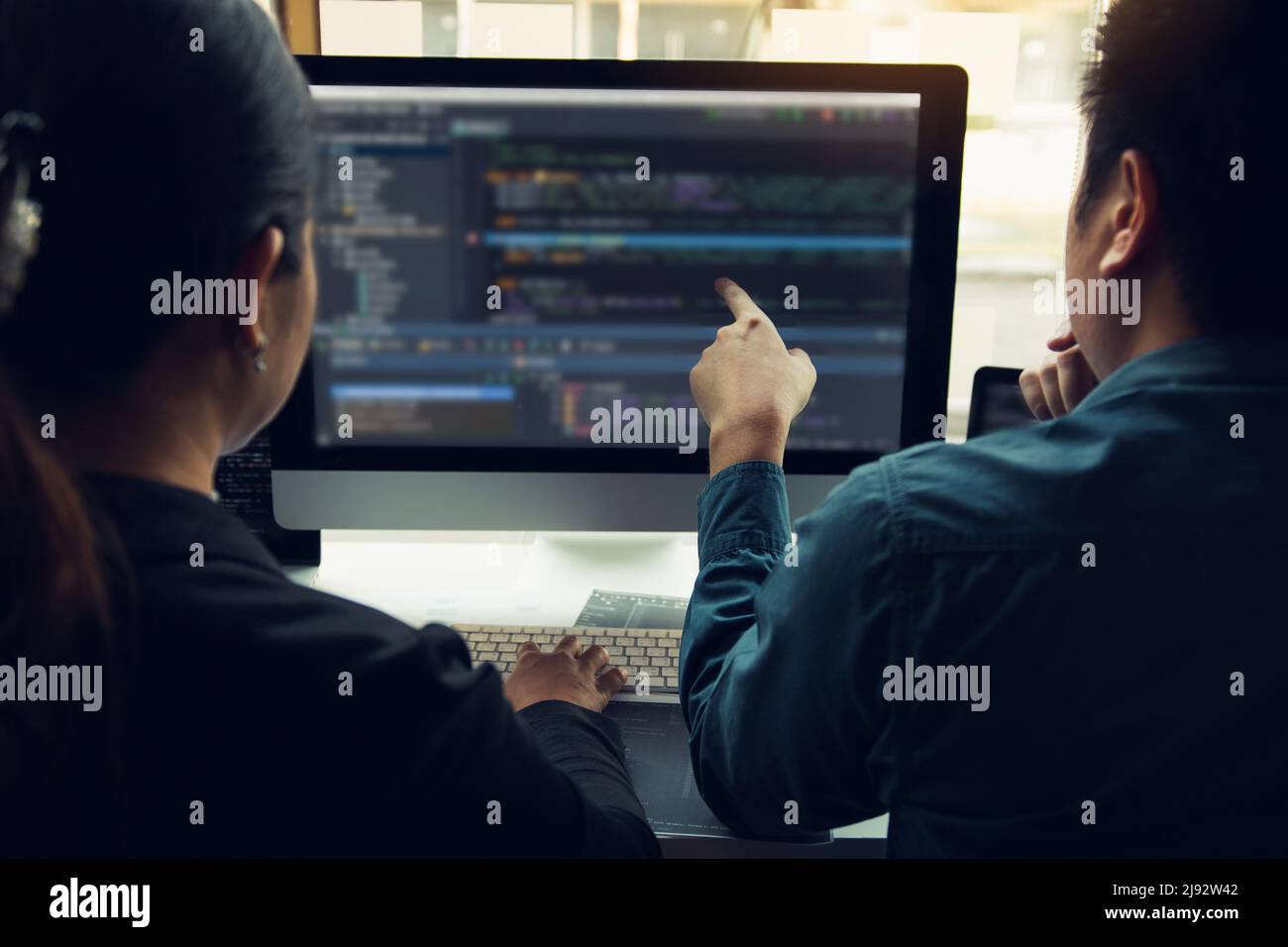 Two software developers are analyzing together about the code written into the program on the computer. Stock Photo