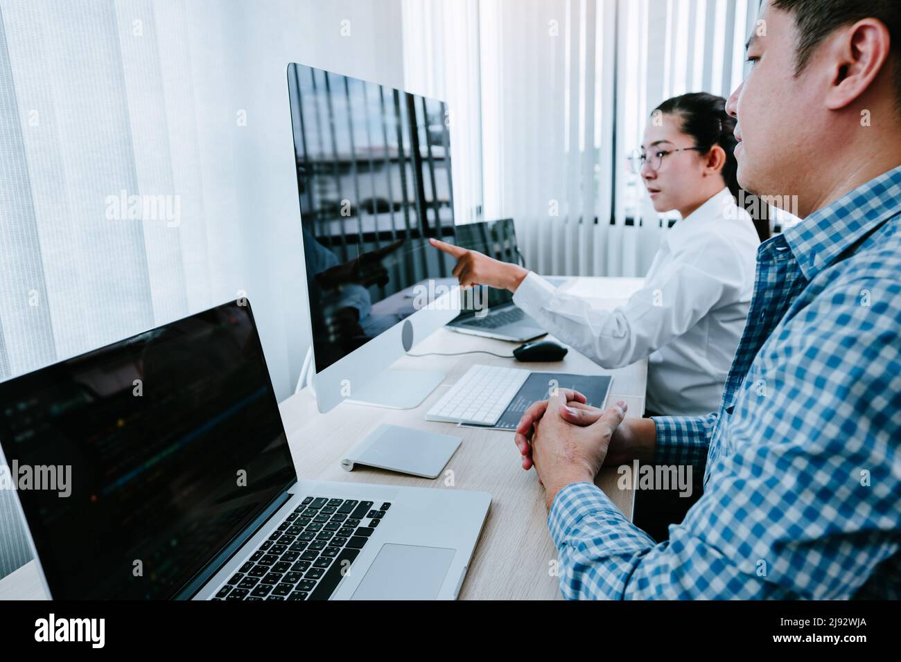 Two partnerships developing programming and coding technologies working on laptop and analyzing together. Stock Photo