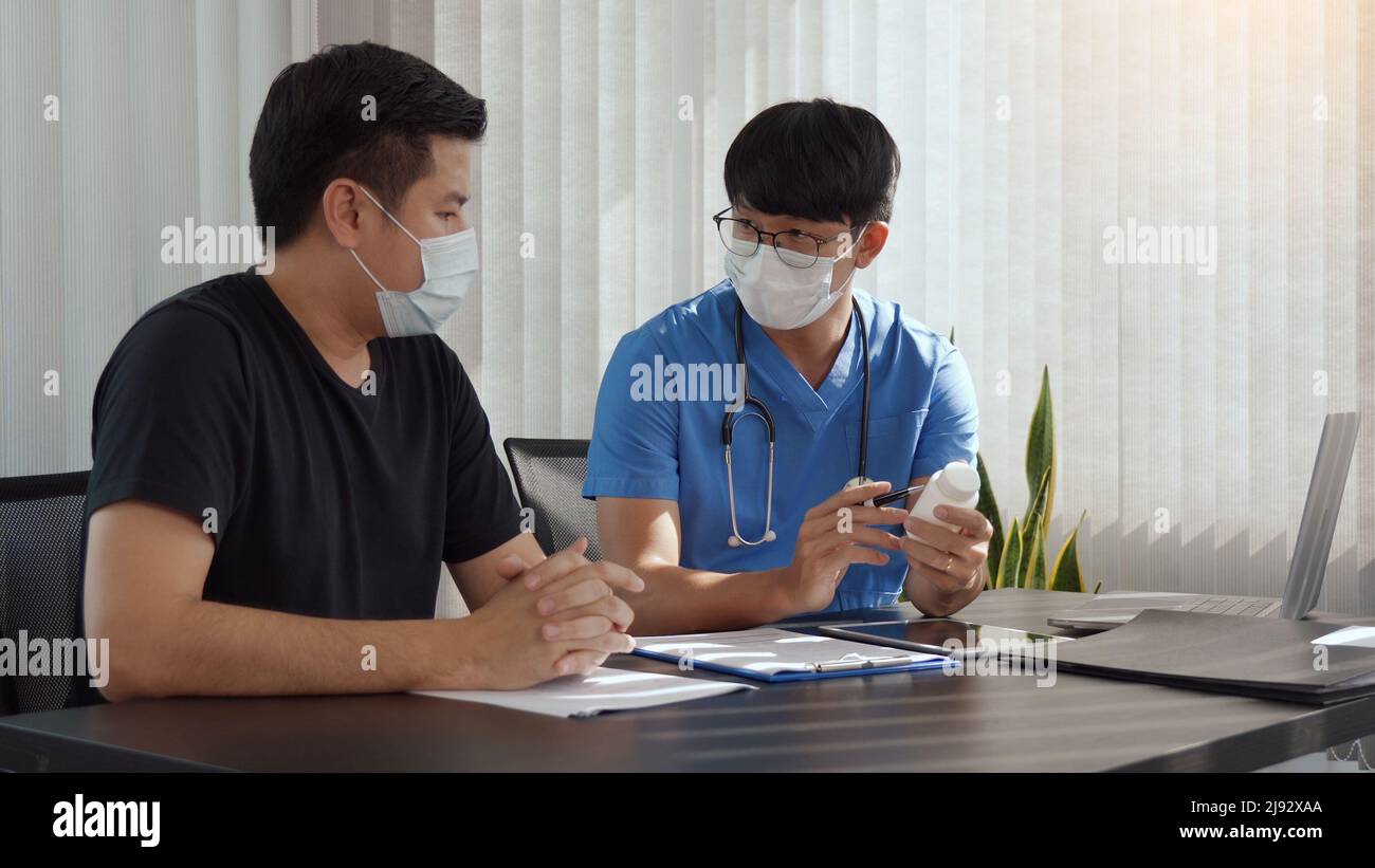 Confident doctor man holding a pill bottle while talking with a senior
