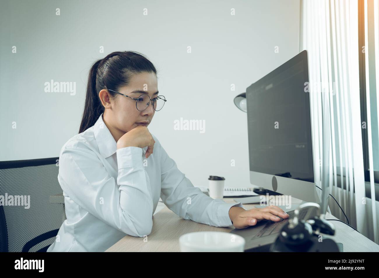 Asian female software developer is worried about analyzing code-based systems at his office. Stock Photo