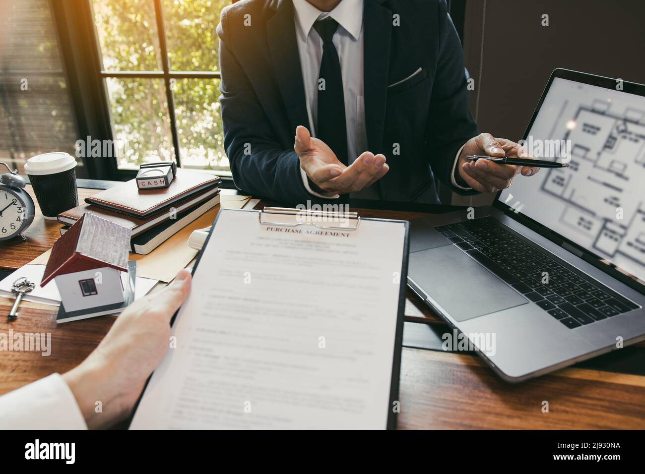 Agents are using pens pointing to blueprint home design on laptop ...