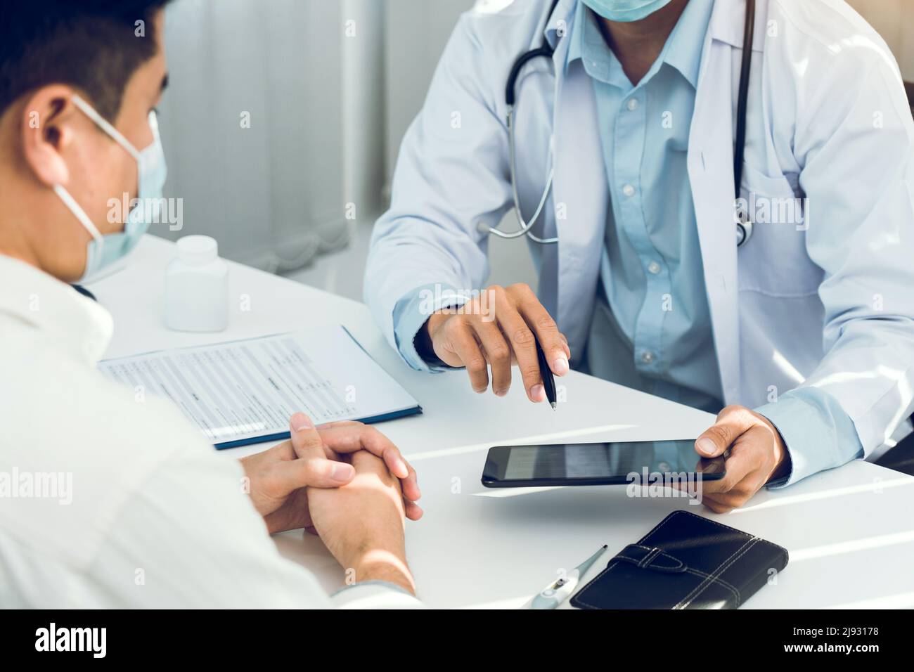Doctors are explaining the treatment of a sick patient in tablets while ...