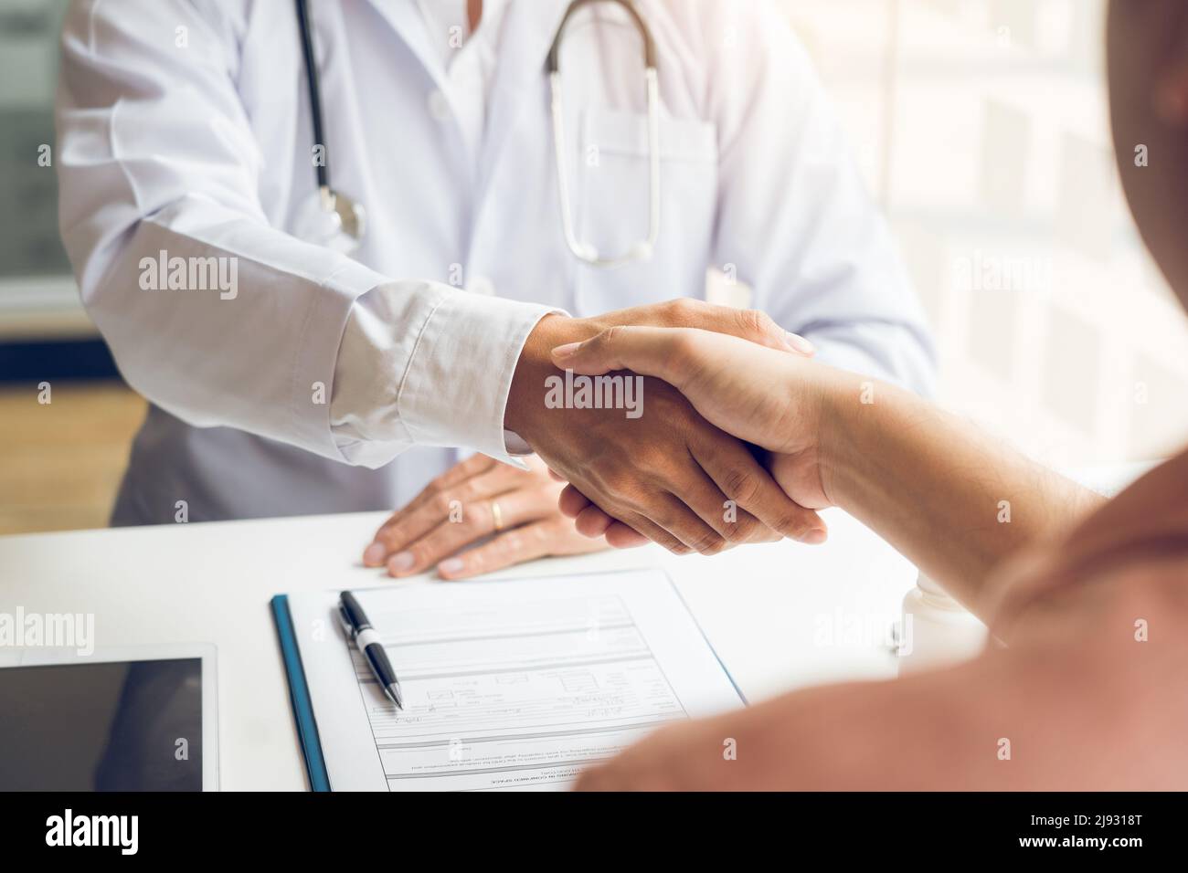 Doctor shaking hands with older patient in the clinic room Stock Photo