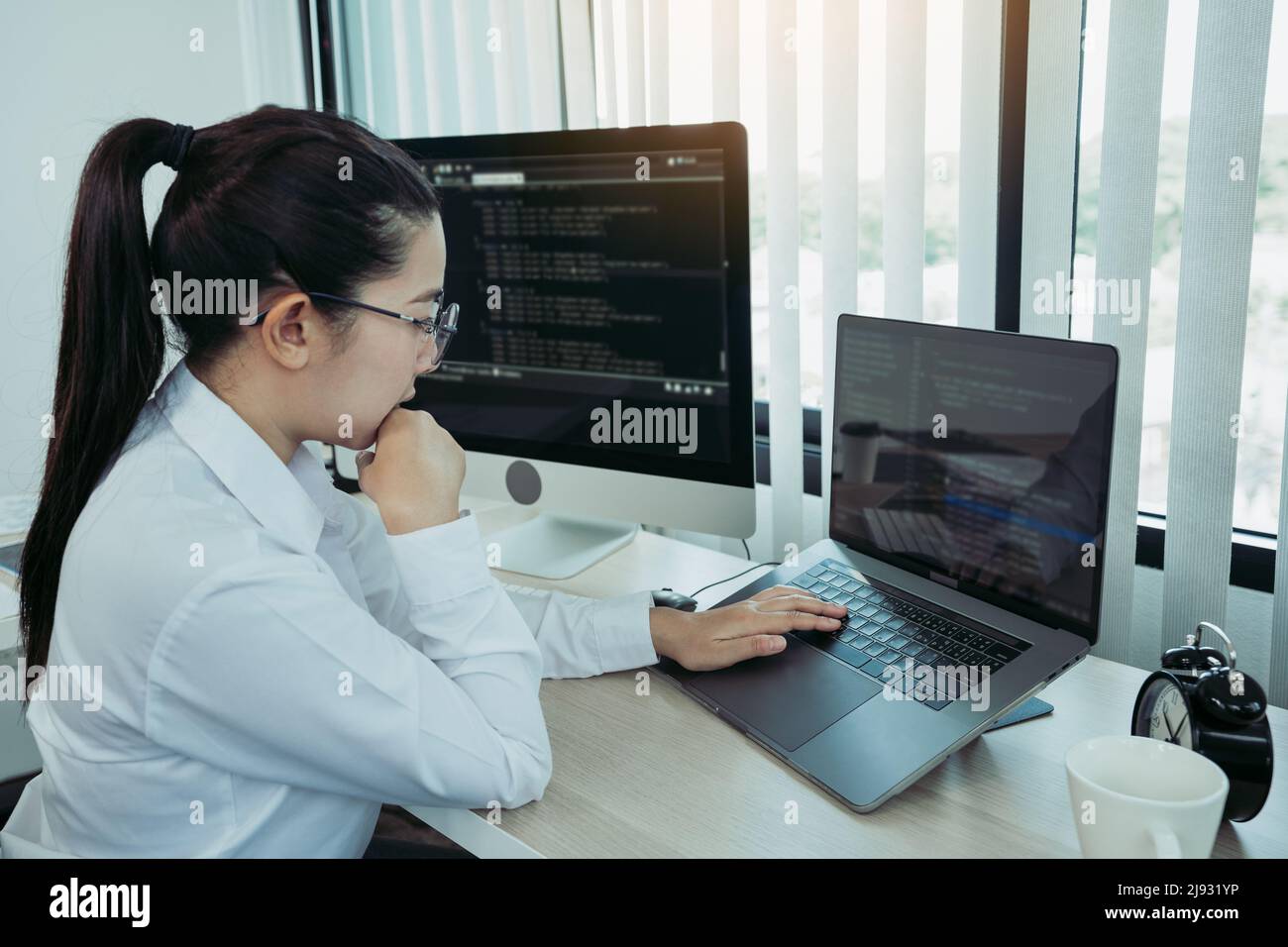 Asian female software developer is worried about analyzing code-based systems at his office. Stock Photo