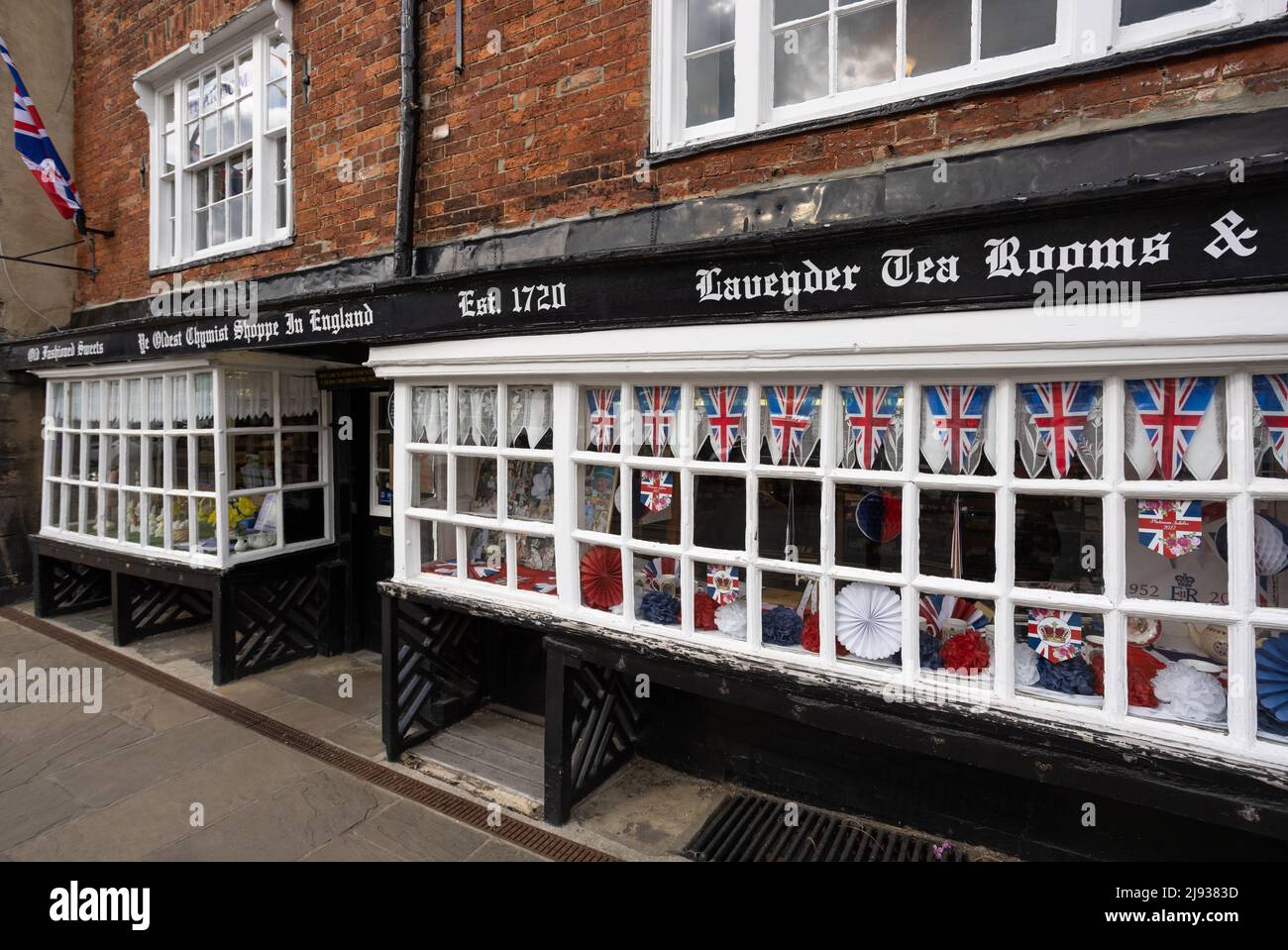 Front of oldest Chemist Shop in Knaresborough, UK. White window with little union jack flags Stock Photo