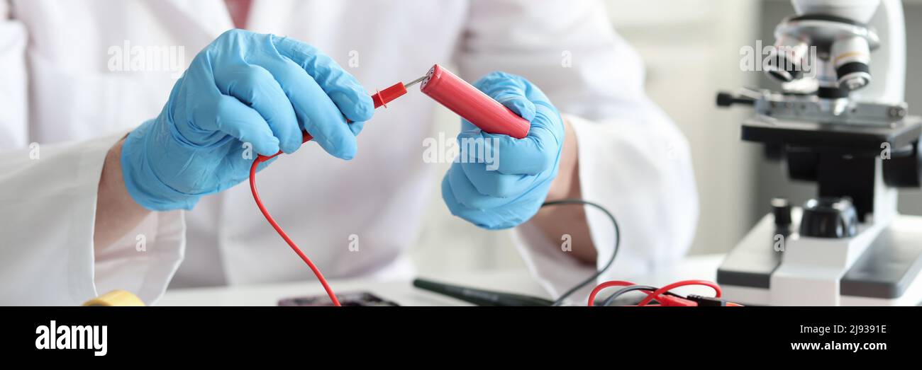 Master repairman checking battery charge using tester closeup Stock Photo