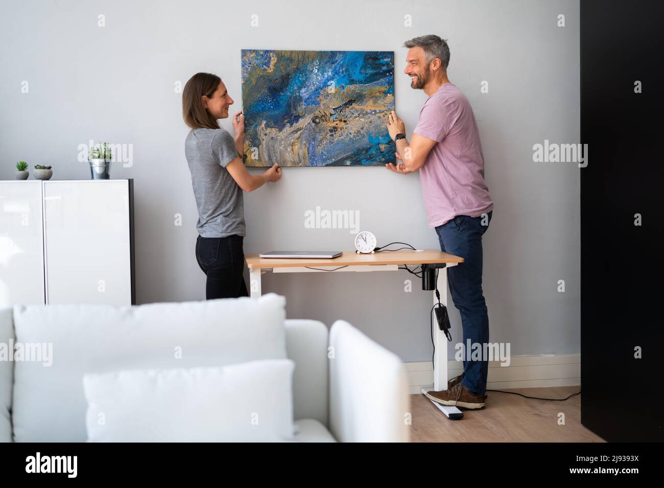 Happy Couple Hanging Painting. Wall Decoration At Home Stock Photo
