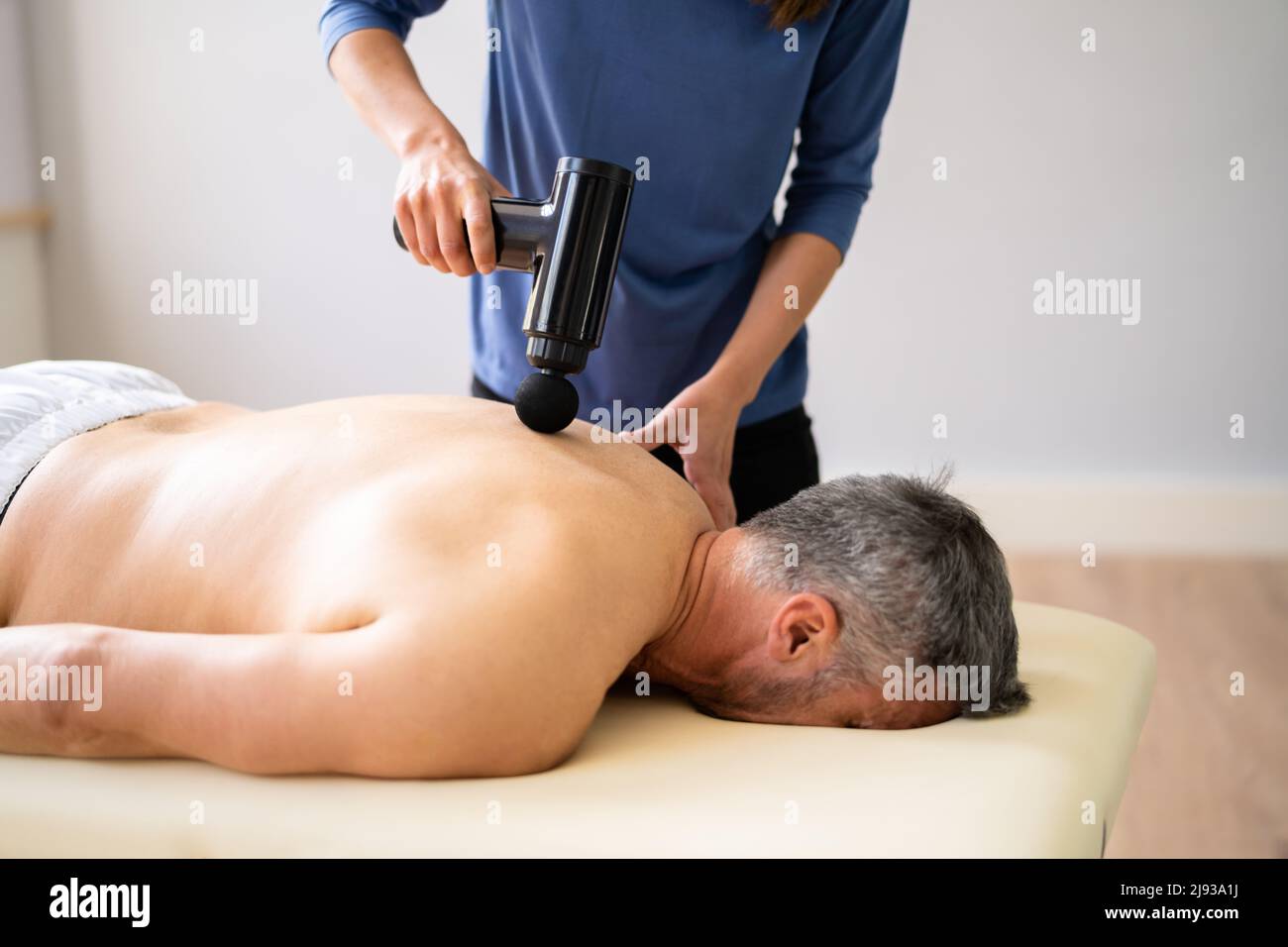 Percussion massager of deep muscle tissues for athletes, relaxes relieves  pain. Handheld wireless professional therapeutic shock massage gun Stock  Photo