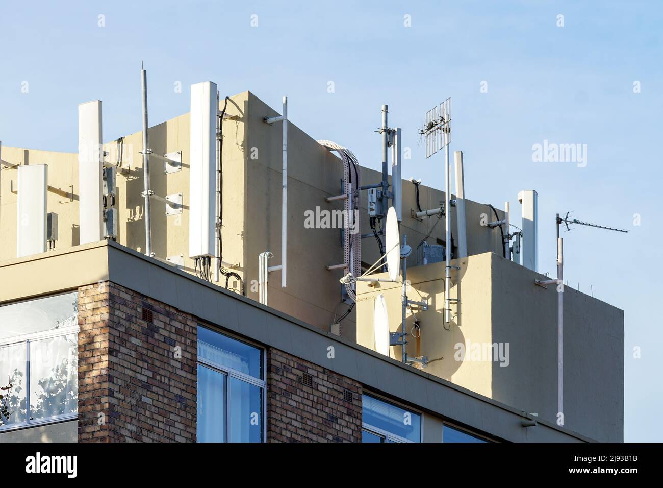 closeup of telecommunication aerials and satellite dishes for tv reception on an apartment building concept technology in South Africa Stock Photo