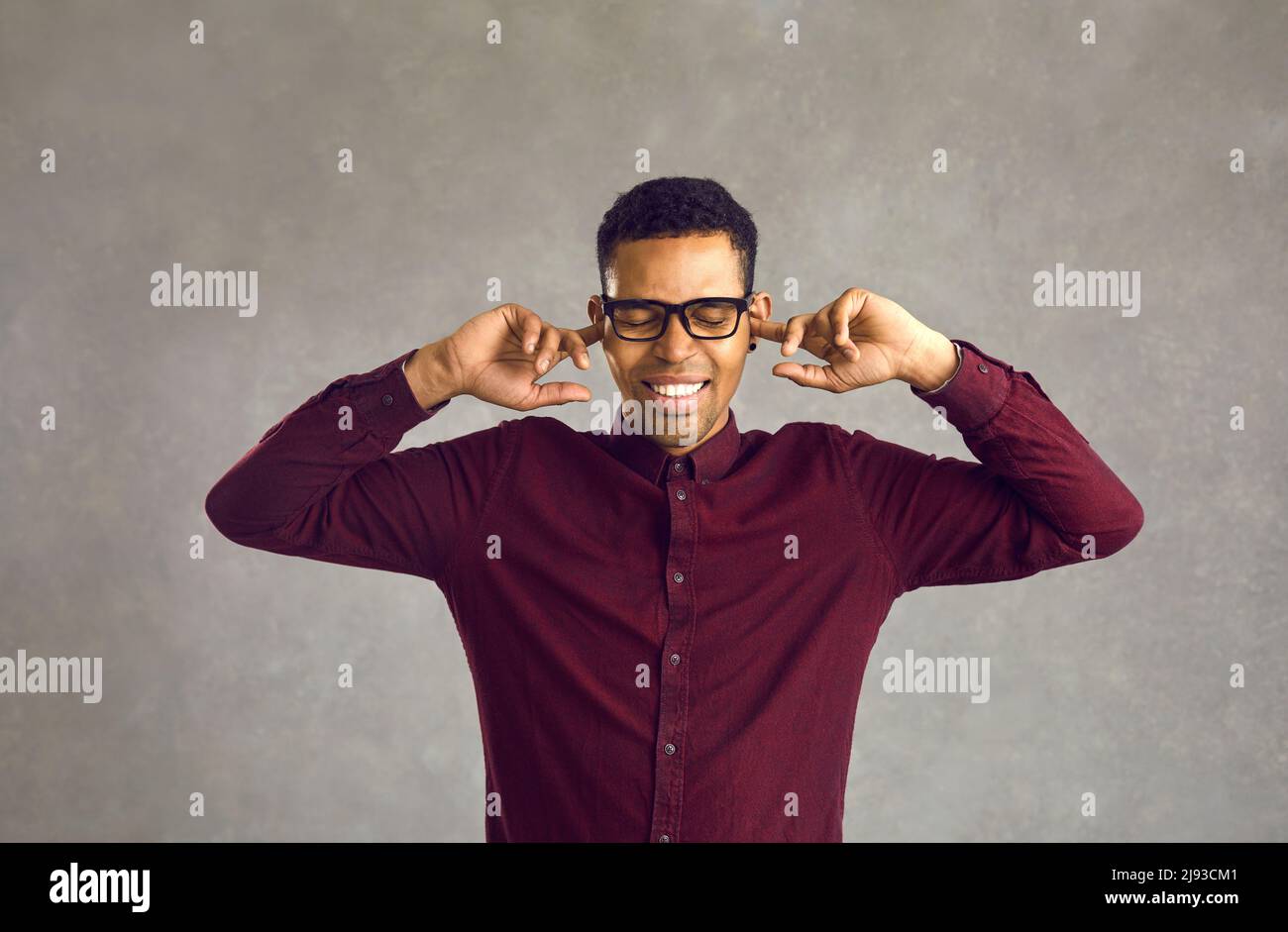 Man closes ears with fingers or earplugs to avoid listening to noise or unsolicited advice Stock Photo