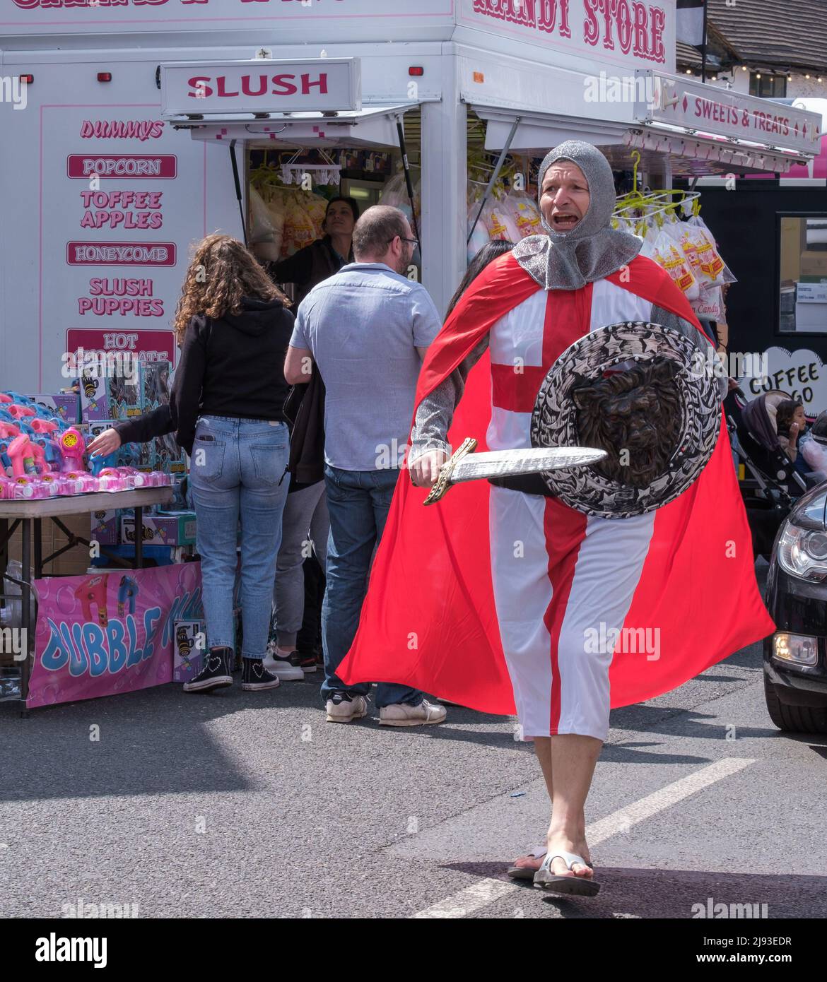 Man dressed as St George, with sword and shield walks in the street at 2022 St George’s Day Celebration. Pinner, Harrow, Greater London, England. Stock Photo