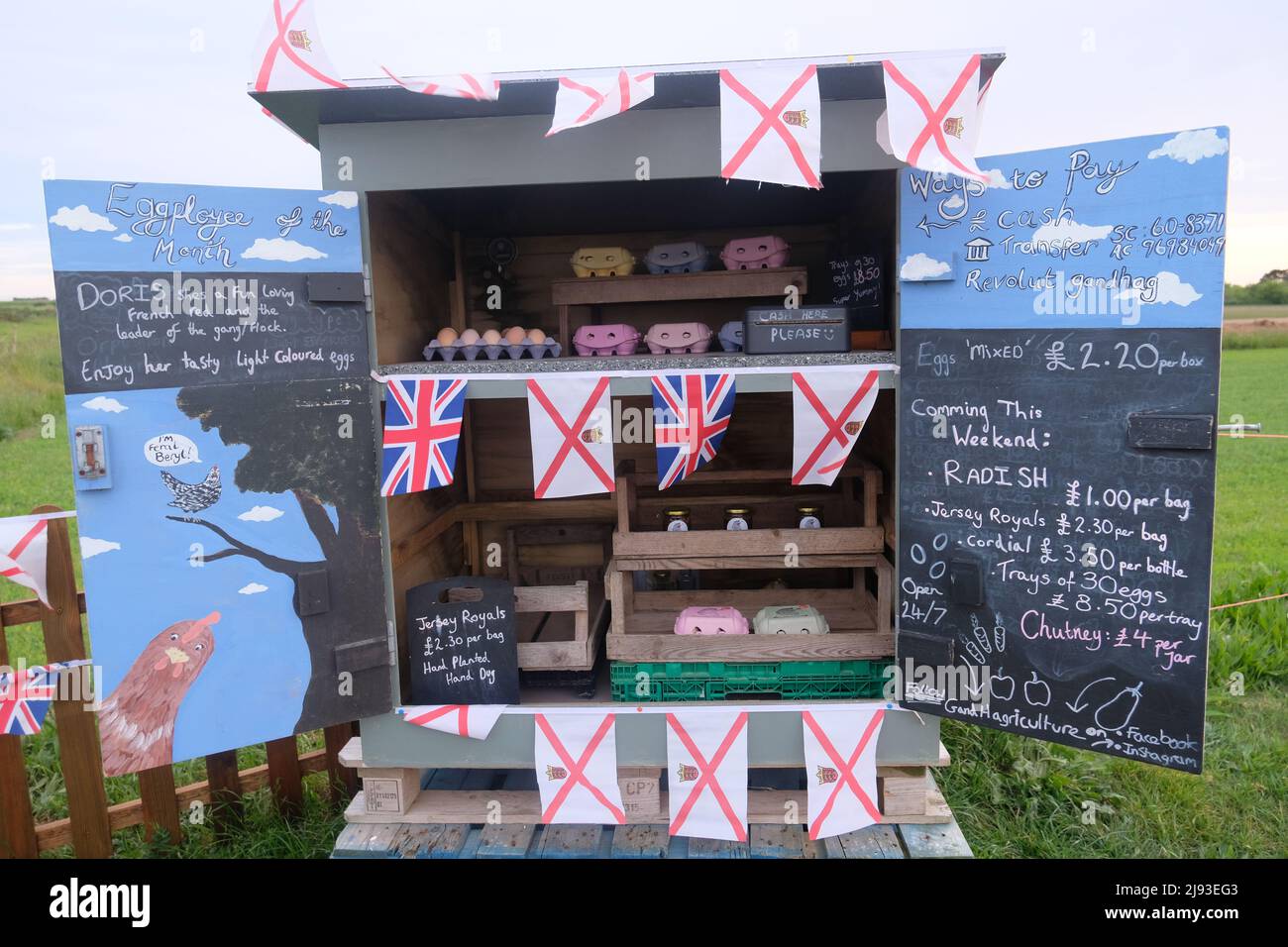 Unstaffed brightly painted honesty stall belonging to G & H Agriculture selling hedge veg St Peter, Jersey, Channel Islands flags for Liberation Day Stock Photo