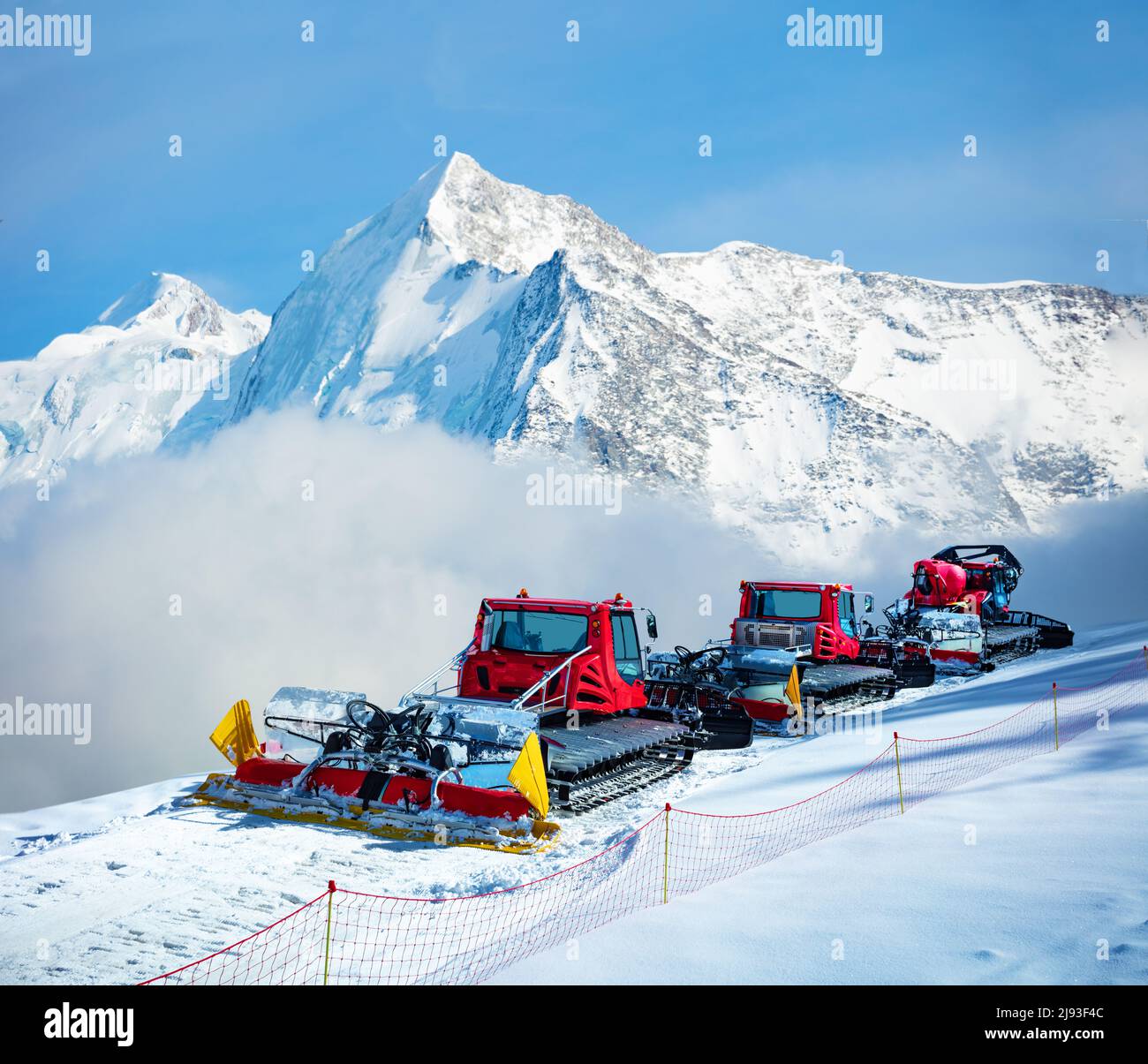 Group of snow groomers over Alps mountain summits Stock Photo
