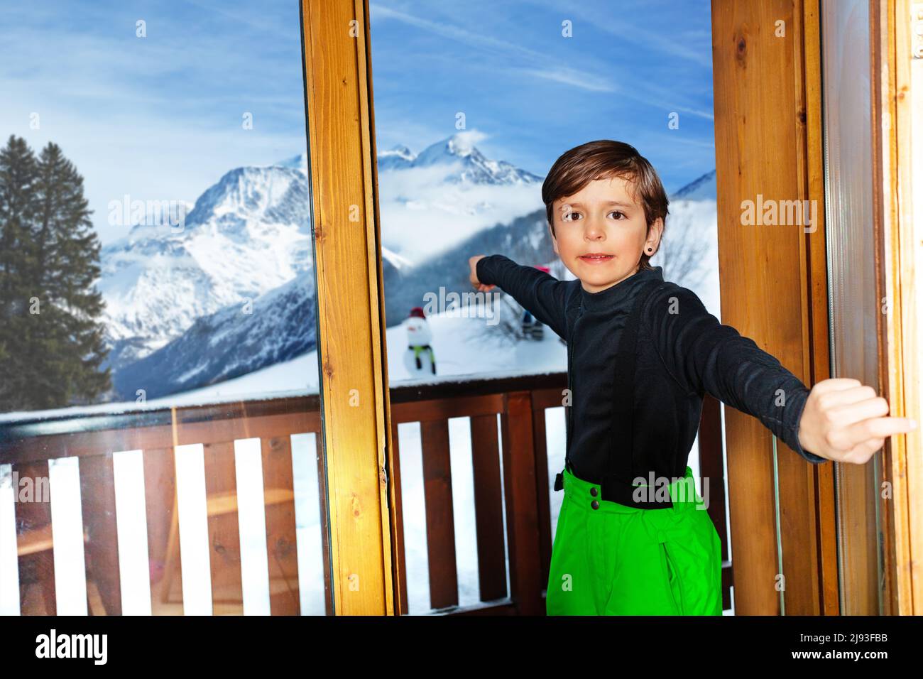 Boy in ski outfit open the door to mountain peaks panorama Stock Photo
