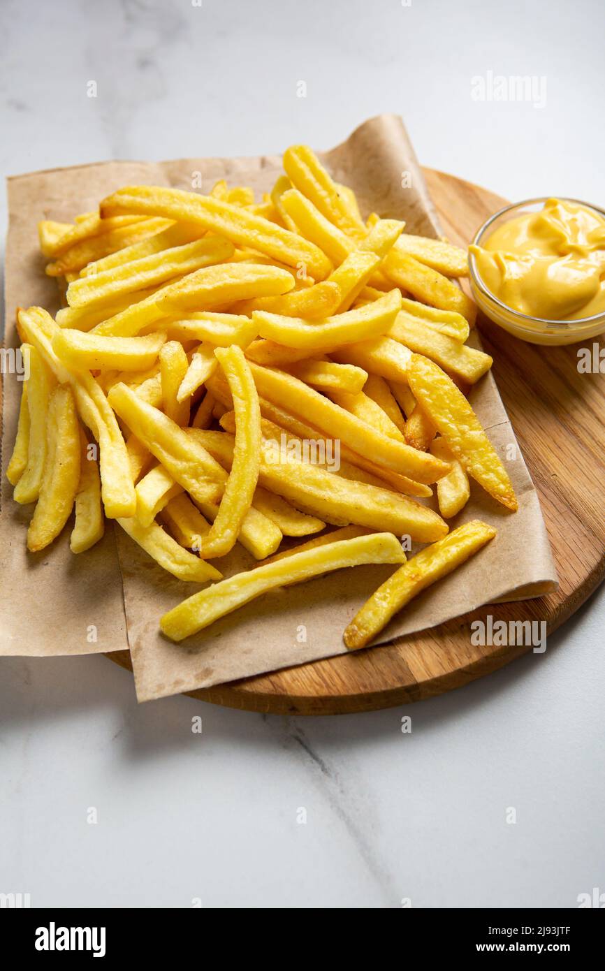Food concept yellow potato french fries on platter and cheese sauce close up Stock Photo