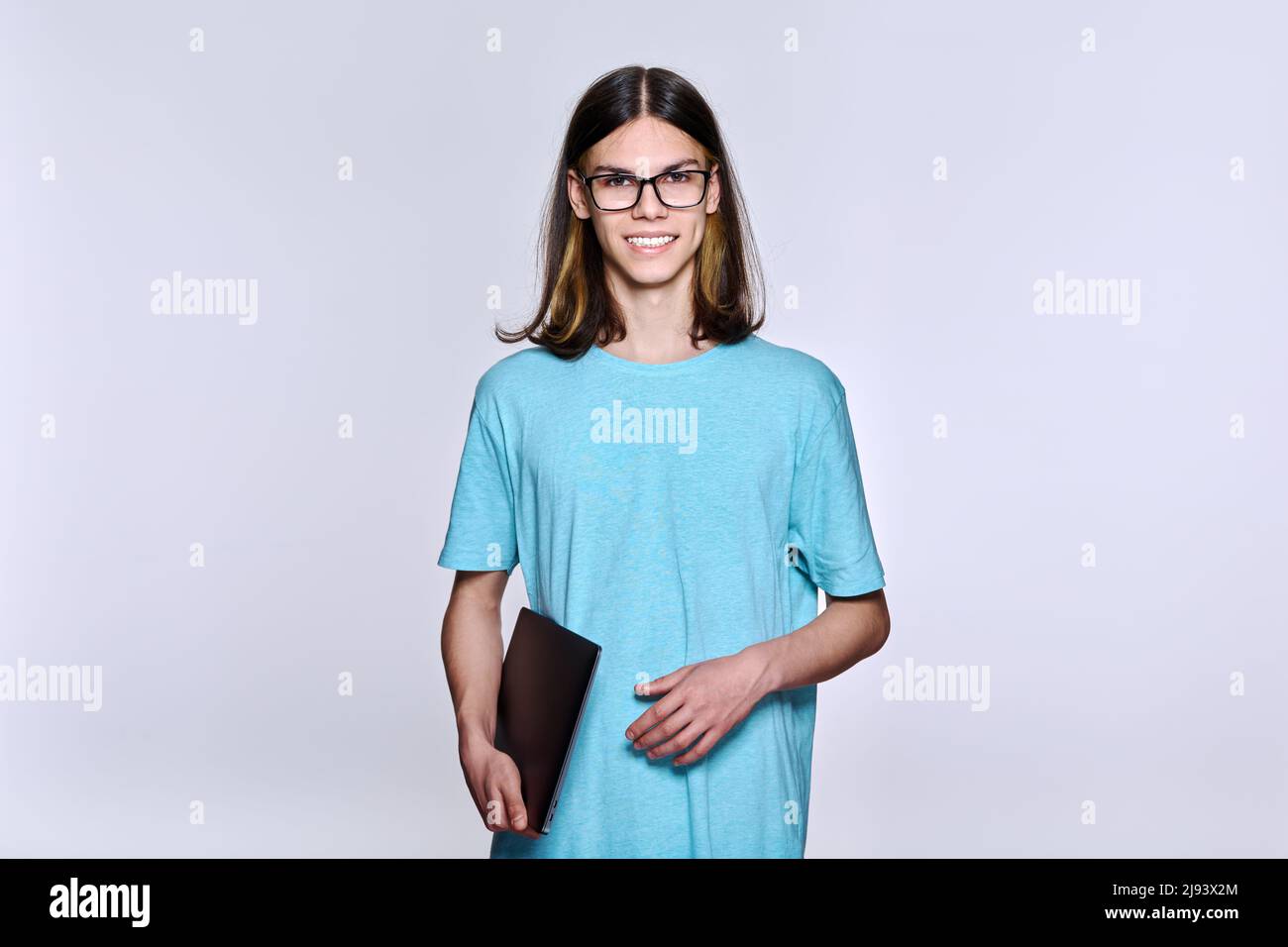 Portrait of positive teenage student guy with glasses with laptop