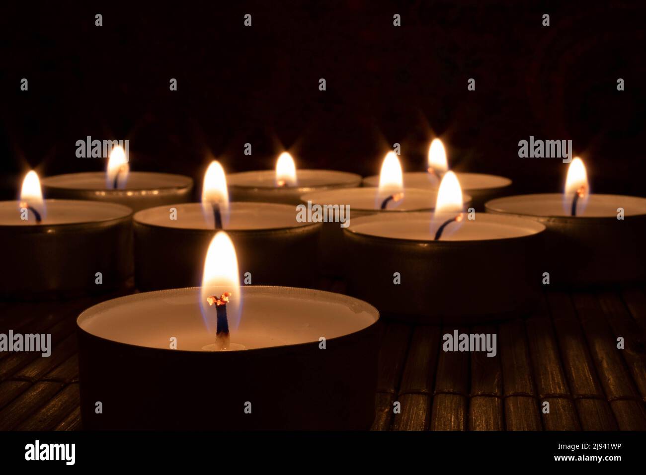 Burning Tealight Candles in Darkness – Warm and Peaceful Ambiance Stock Photo