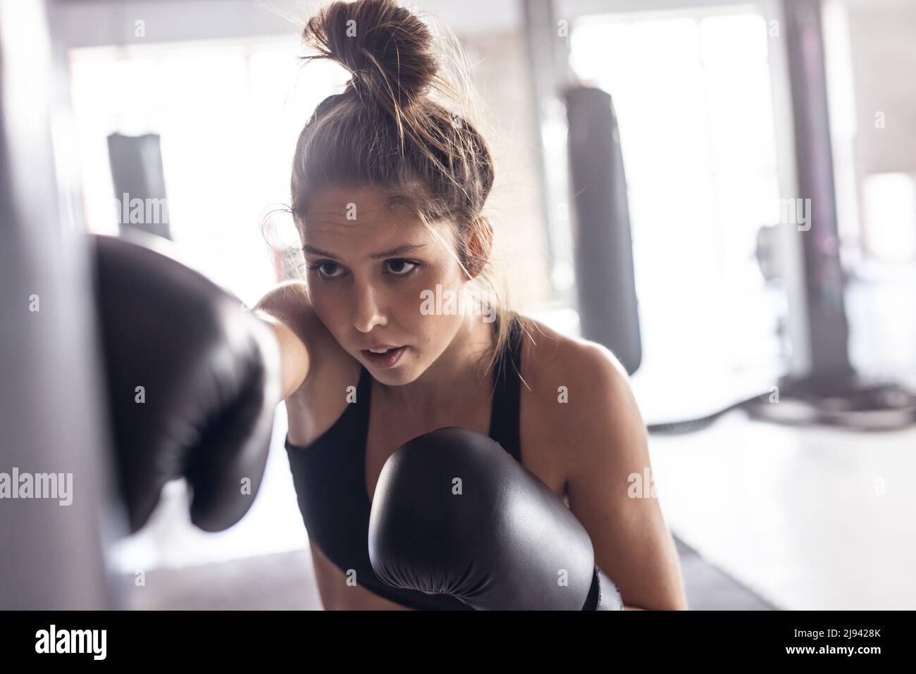 Confident caucasian young female boxer wearing black gloves hitting
