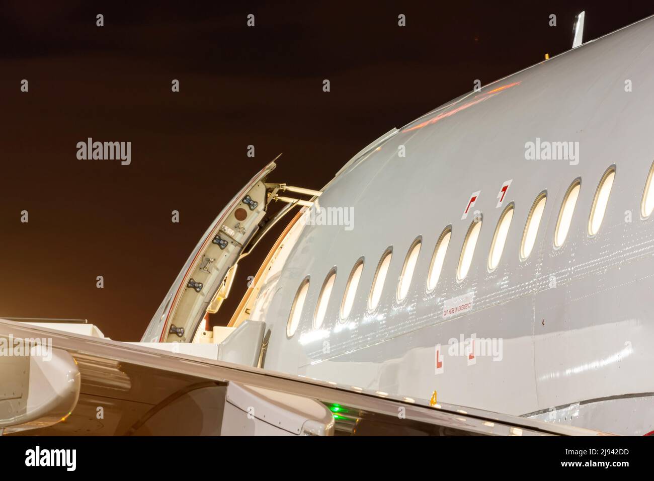 Airplane fuselage at night with open door and luminous portholes Stock Photo