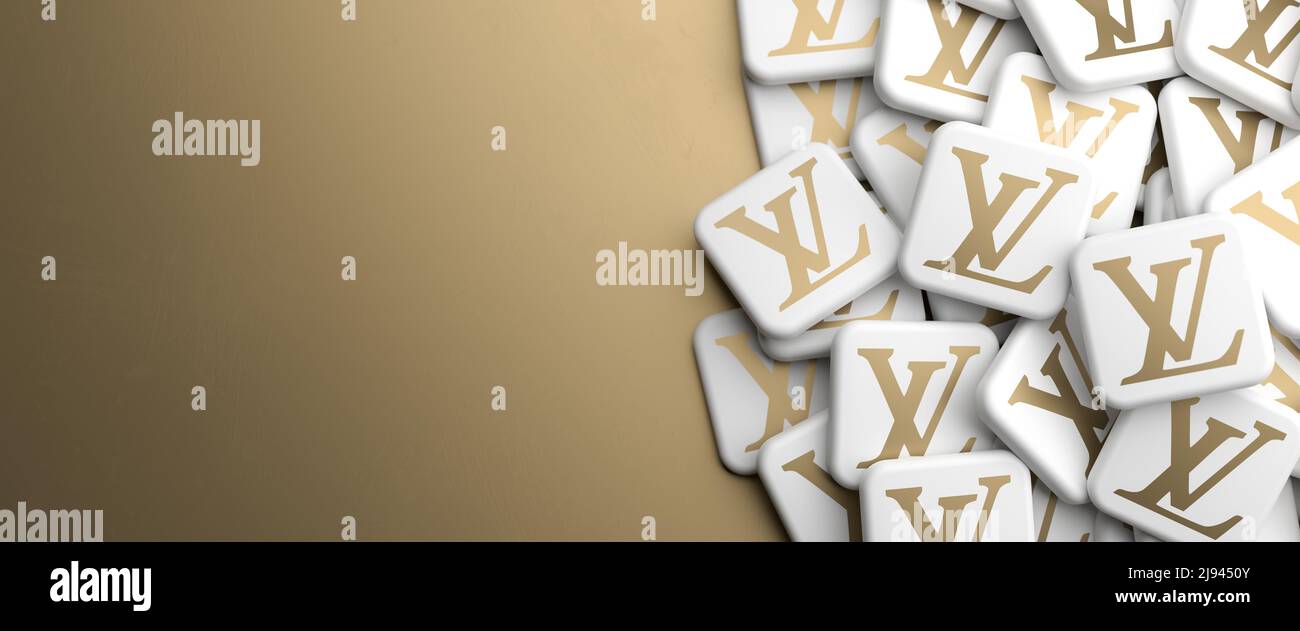 Logos of the luxury goods brand Louis Vuitton on a heap on a table. Copy space. Web banner format. Stock Photo
