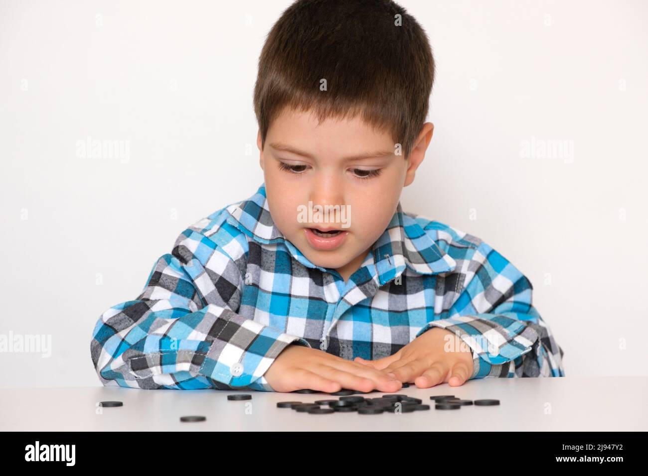 A 4-year-old boy is learning to count, teaching black numeracy chips for preschoolers Stock Photo