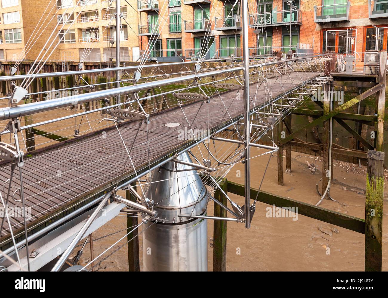 Stainless steel cable stayed pedestrian swing bridge over St Saviours Dock in London, UK Stock