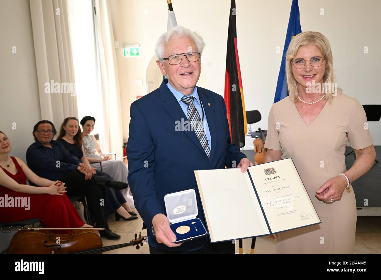 Munich, Germany. 20th May, 2022. Herbert Fitzka, longstanding commitment to the 'Katholische Arbeitnehmer Bewegung (KAB) Augsburg' is honored at the award ceremony of the Bavarian State Medal for Social Merit in the Orangery of the Nymphenburg Palace by Ulrike Scharf, Minister of State in the State Ministry for Family, Labor and Social Affairs. Credit: Felix Hörhager/dpa/Alamy Live News Stock Photo