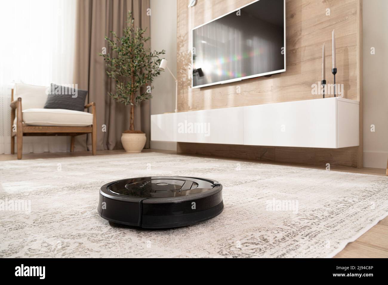 Robotic vacuum cleaner on the floor in cozy modern living room Stock ...