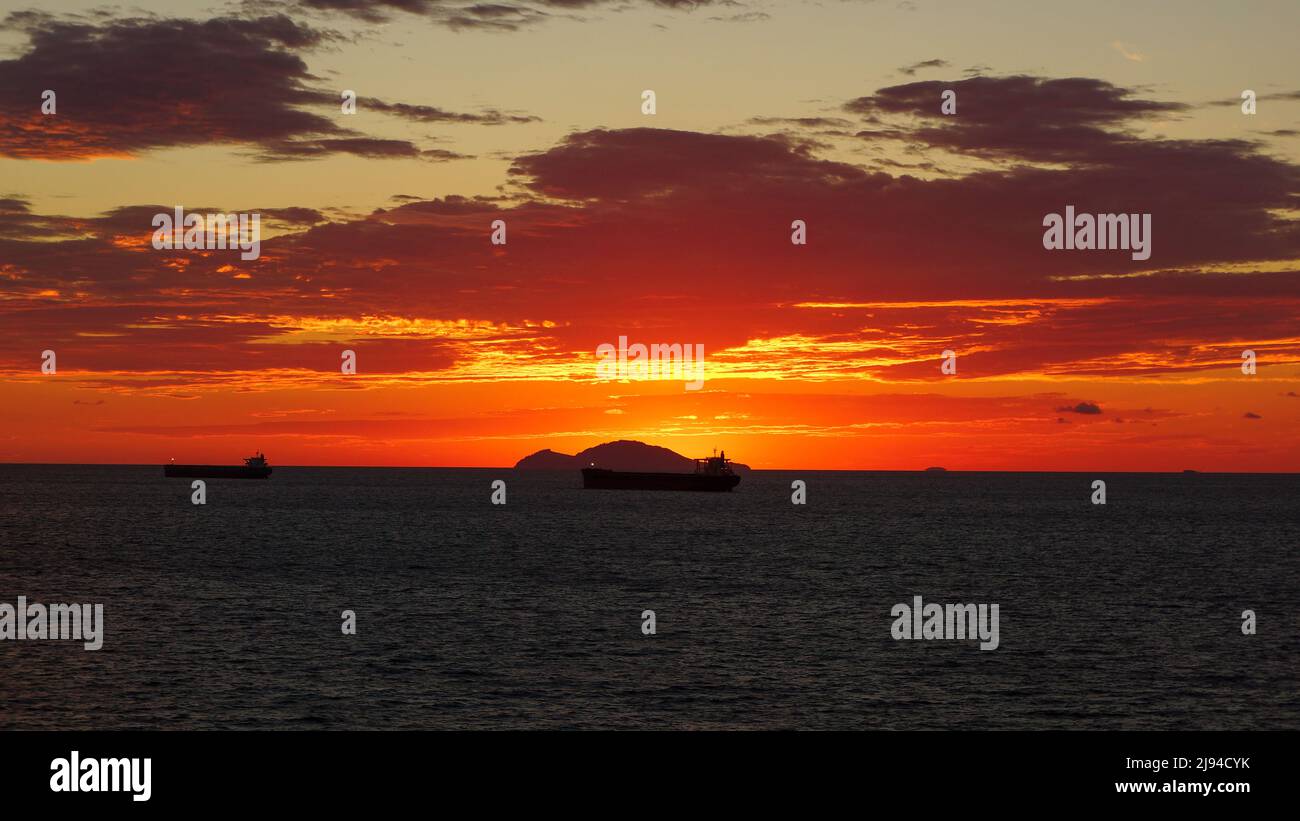 Anchored ships at sea near an island with stunning cloud formations and