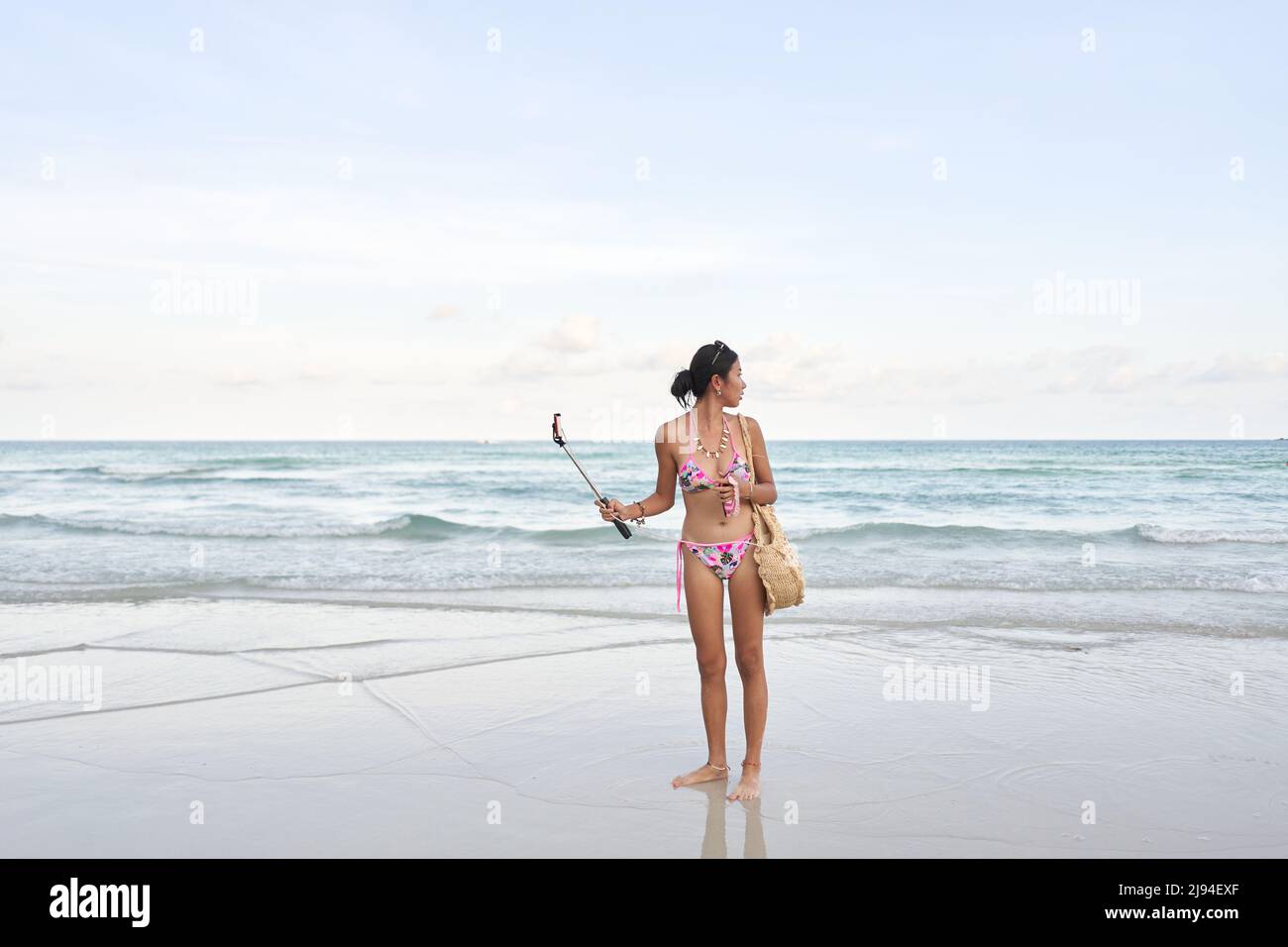 Streamer holding a mobile with a stick while looking distractedly at the sea Stock Photo